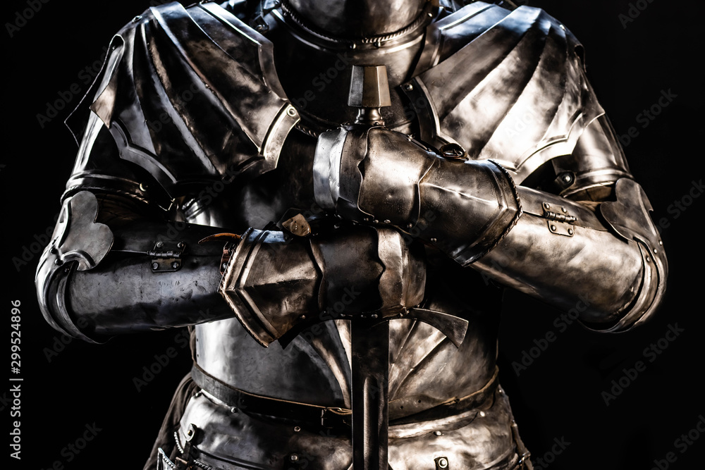 cropped view of knight in armor holding sword isolated on black